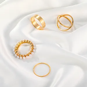 Detail view of vintage gold ring set featuring pearl embellishment on white silk.
