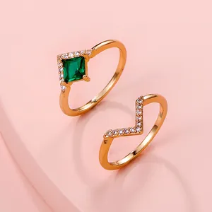 Detail view of gold adjustable rings with square green emerald-style gem and V-shape band.