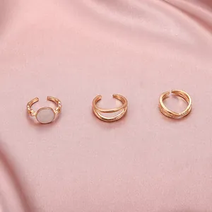 Close-up of three rose gold open rings from a multi-piece vintage set on pink satin