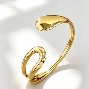 Detail shot of a polished gold geometric open cuff bracelet featuring sleek elegant curves