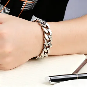 Gros plan d'un bracelet gourmette en acier titane pour homme au poignet sur un carnet de notes