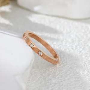 Close-up of elegant rose gold ring with three inset diamonds on white background.
