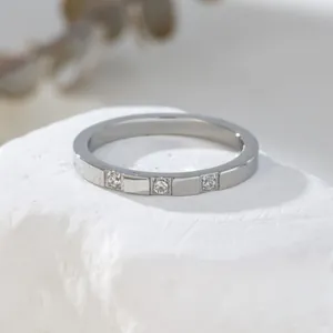 Macro shot of silver ring featuring three inlaid sparkling crystals on white rock
