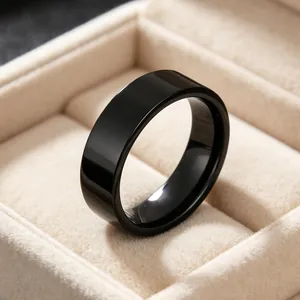 Macro view of a 6mm polished black stainless steel band ring in a beige jewelry box.