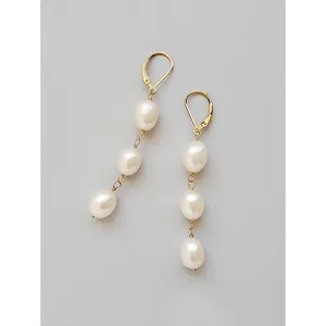 Vue détaillée de boucles d'oreilles pendantes à trois perles baroques et or jaune.