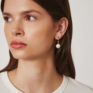 Vue détaillée de boucles d'oreilles élégantes en perles baroques portées par un mannequin