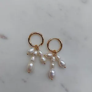 Détail de grappes de perles baroques sur des boucles d'oreilles créoles dorées