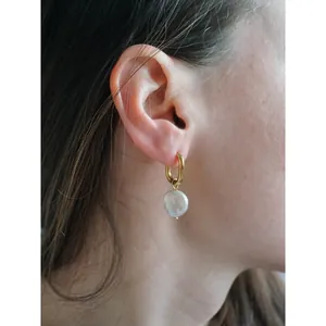 Gros plan détaillé d'une boucle d'oreille en perle baroque naturelle portée à l'oreille