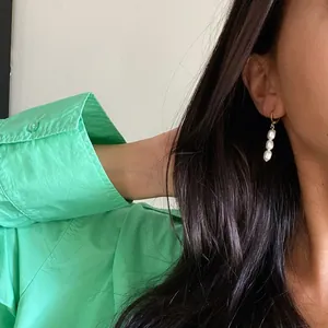 Vue détaillée de boucles d'oreilles en perles baroques naturelles sur un mannequin
