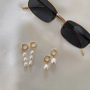 Gros plan détaillé de boucles d'oreilles en perles baroques plaquées or 18k sur tissu.