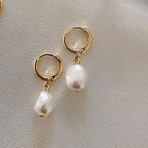 Gros plan de boucles d'oreilles perles baroques élégantes en acier titane plaqué or 18k