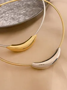 Gros plan de colliers en acier inoxydable avec pendentifs incurvés dorés et argentés.