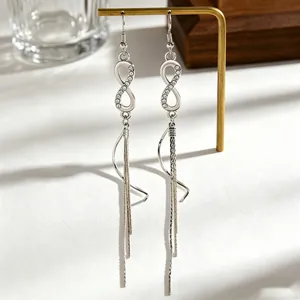 Close-up of silver infinity tassel earrings with rhinestones on a jewelry display stand
