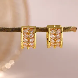 Macro view of gold-plated hoop earrings featuring zircon wheat-ear pattern on a branch
