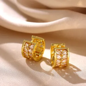 Detailed close-up of gold-plated huggie hoop earrings with marquise-cut cubic zirconia stones.