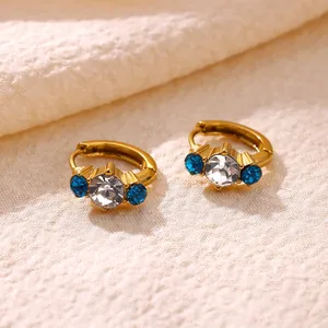 Detailed close-up view of golden copper hoop earrings with clear and blue zircon stones