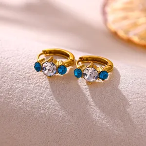 Close-up of gold-plated hoop earrings featuring blue and clear zircon crystals