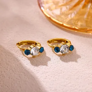 Close-up view of elegant gold hoop earrings set with white and blue zircon stones