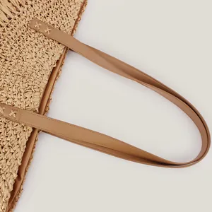 Woven straw shoulder bag detail with sturdy brown leather straps for beach vacation