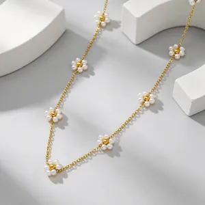 Nahaufnahme einer eleganten Goldkette mit zarten Blumenanhängern aus weißen Perlen