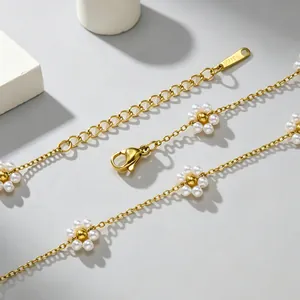 Makroaufnahme einer goldenen Edelstahlkette mit eleganten Blumenanhängern aus Perlen