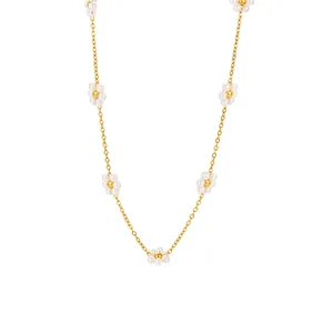 Detaillierte Makroaufnahme einer Goldkette mit zarten Perlen-Gänseblümchen-Anhängern.