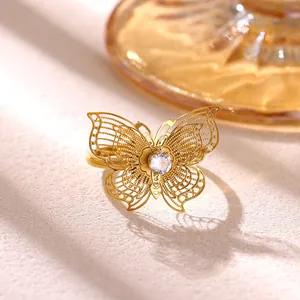Primer plano de anillo mariposa dorado con alas de filigrana y detalle de cristal fino.