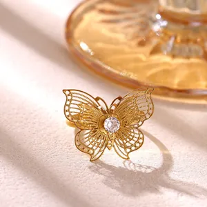 Detalle de un anillo de mariposa chapado en oro con alas filigranas y un circón central brillante.