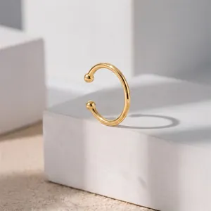 Close-up van een minimalistische vergulde zilveren oorklem op een witte sokkel