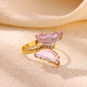 Primer plano de un anillo de mariposa bañado en oro con piedras púrpuras talladas