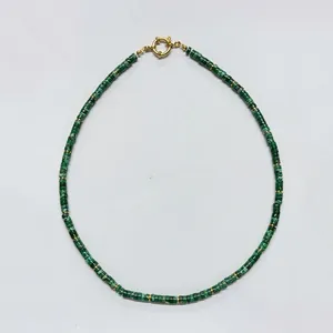 Detail view of a green natural stone beaded necklace featuring a gold spring ring clasp.