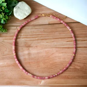 Detailed view of natural pink semi-precious stone beaded necklace on wood grain