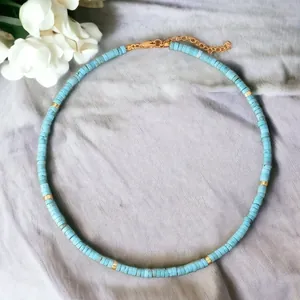 Detailed view of handmade turquoise beaded necklace with elegant gold accents on soft fabric