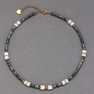 Detailed view of a beaded necklace with green semi-precious stones and white discs