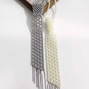 Vue détaillée de colliers cravate en perles argentées et blanches avec des pompons.