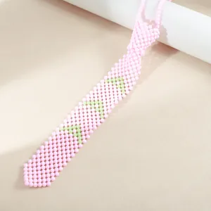 Collier cravate en perles roses avec motifs verts sur fond beige texturé élégant