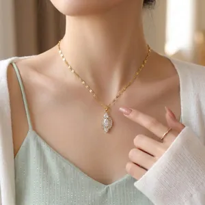 Gros plan d'un collier en acier titane doré avec pendentif en cristal marquise.