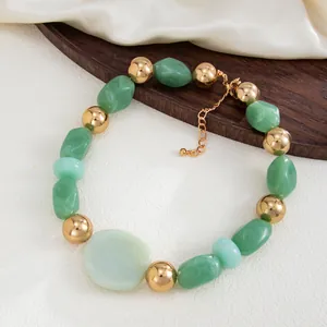 Macro view of a chunky green marbled resin necklace with decorative gold beads