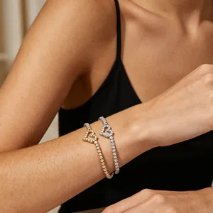 Vue détaillée de bracelets de tennis élégants en forme de cœur dorés et argentés sur le poignet