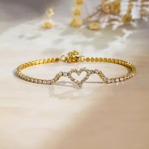 Gros plan d'un bracelet de tennis cœur doré avec oxydes de zirconium sur fond chaleureux.