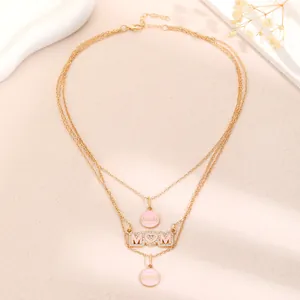 Close-up detail of a gold-plated layered Mother's Day necklace featuring pink MOM charms