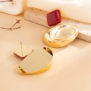 Detailed macro view of French retro gold earrings with dark red geometric accents.