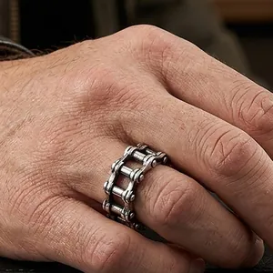 Detail view of a men's vintage hollow bicycle chain ring in 316 stainless steel on finger.