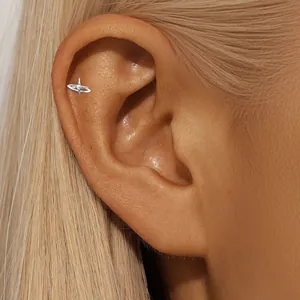 Detailed macro view of a silver orb-shaped stud earring worn on the ear cartilage