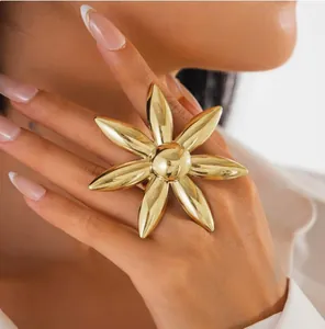 Vue détaillée d'une bague fleur dorée surdimensionnée sur la main du mannequin