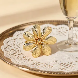 Grande bague ouverte fleur de soleil dorée avec pétales en spirale sur plateau élégant