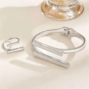 Detailed view of silver-toned geometric bangle and open ring set on light background