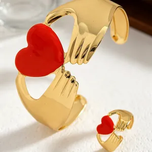 Detailed view of the gold-plated hugging hands bracelet and ring set with red enamel hearts
