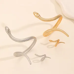 Detailed view of textured gold and silver snake-shaped open bracelet and ring set