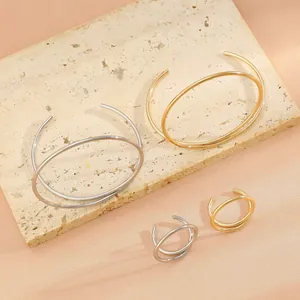 Detailed view of the geometric open metal bracelet and ring set in gold and silver finishes.